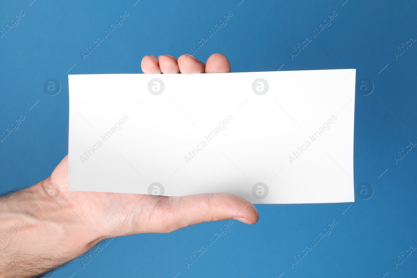 Photo of Man holding flyer on blue background, closeup. Mockup for design
