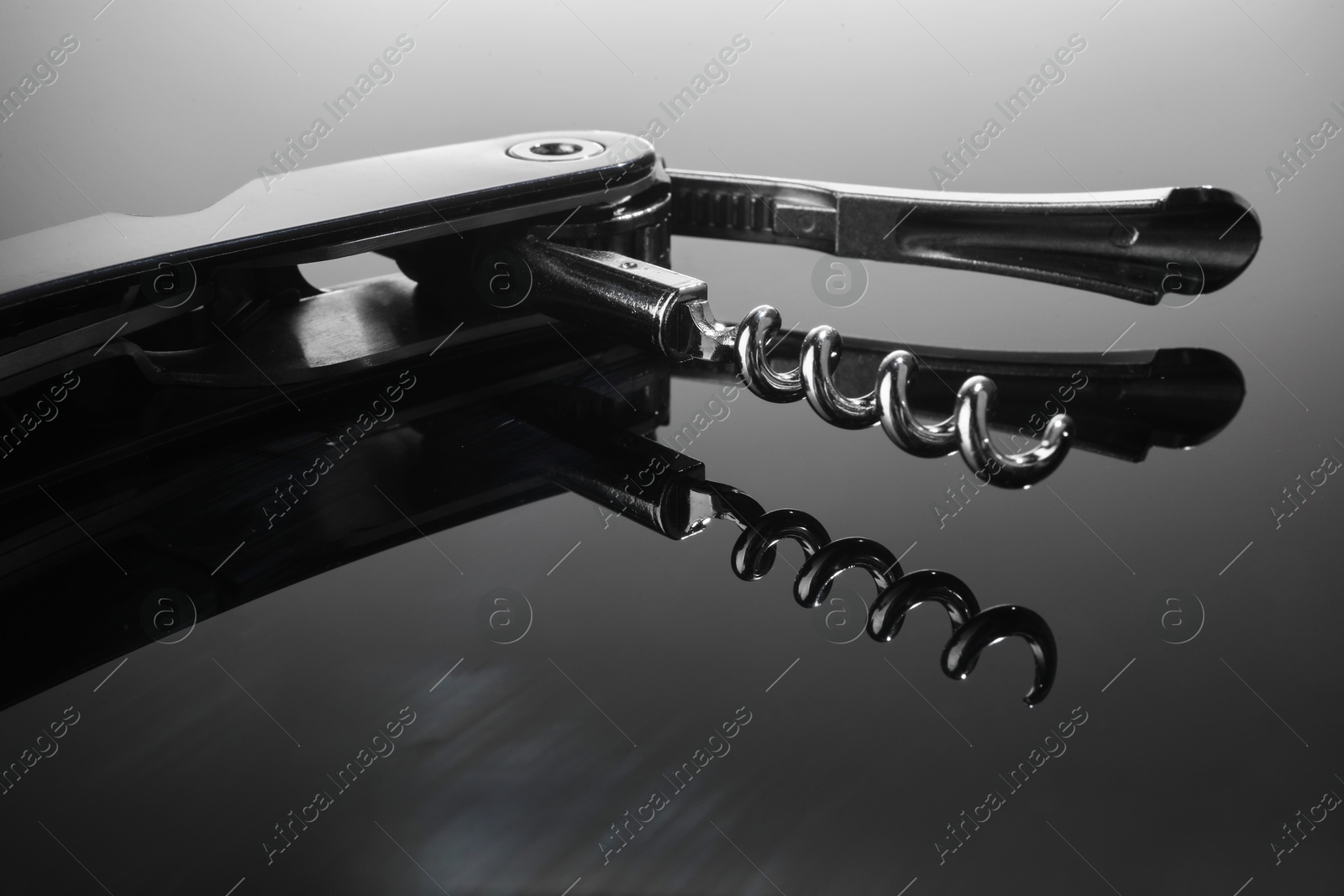 Photo of One corkscrew (sommelier knife) on mirror surface, closeup