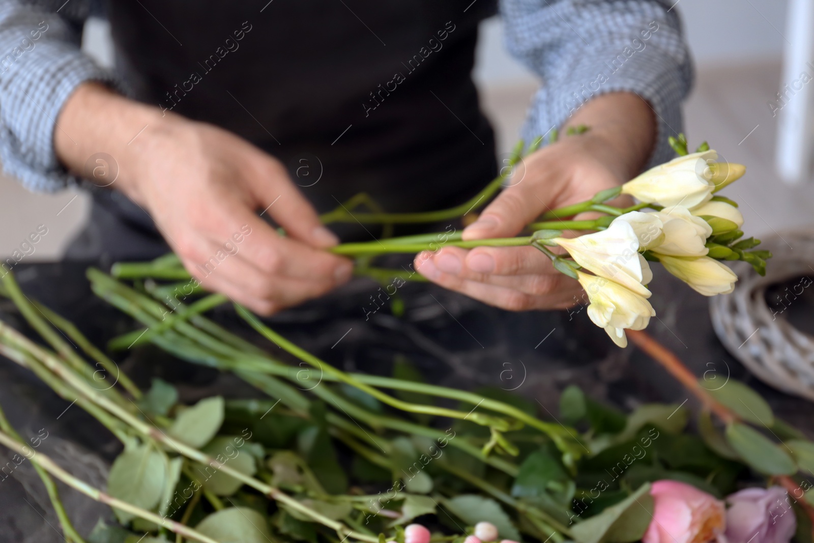 Photo of Male florist creating beautiful bouquet at table, closeup