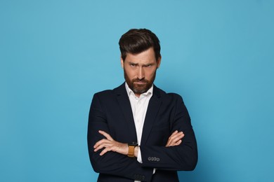 Photo of Portrait of offended bearded man on light blue background. Space for text