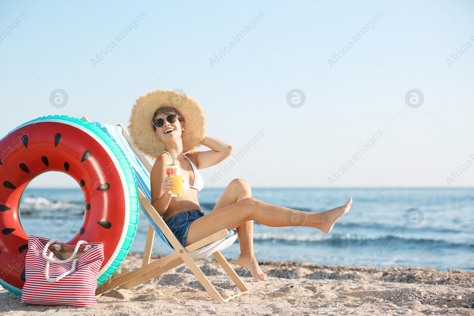 Photo of Young woman with cocktail in beach chair at seacoast. Space for text