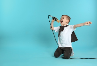 Photo of Cute funny boy with microphone on color background. Space for text