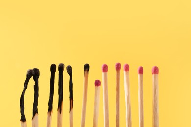 Burnt and whole matches on yellow background. Space for text