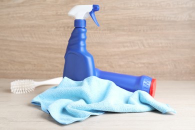 Photo of Microfiber cloth, brush and detergents on white wooden table