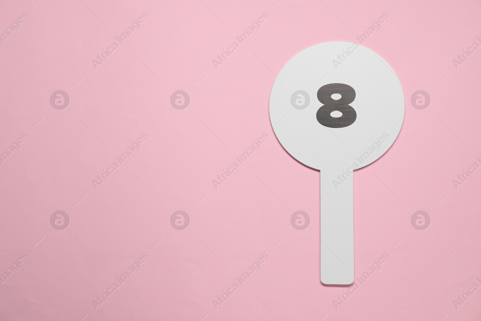 Photo of Auction paddle with number 8 on pink background, top view. Space for text
