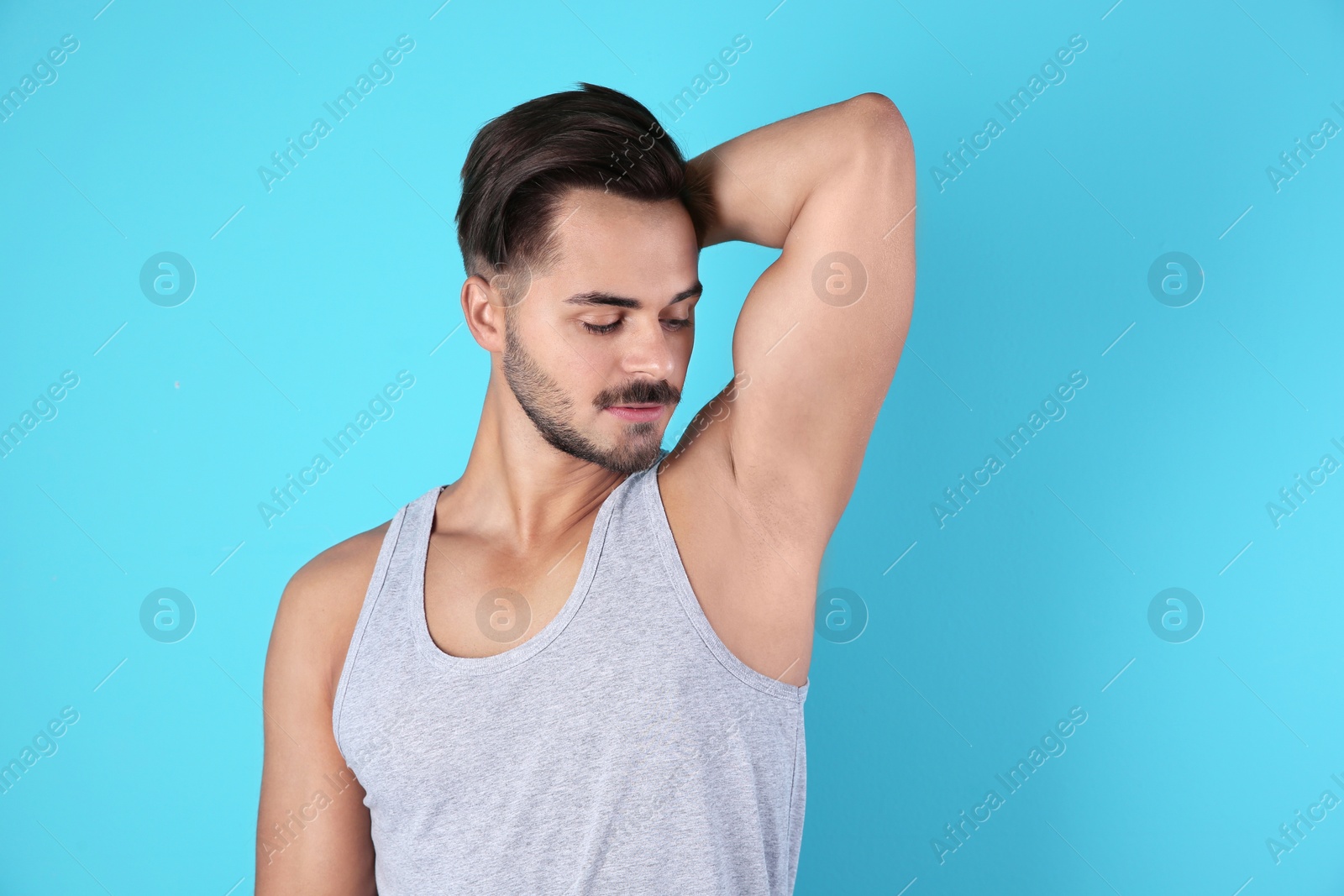 Photo of Handsome young man showing armpit on color background. Using deodorant