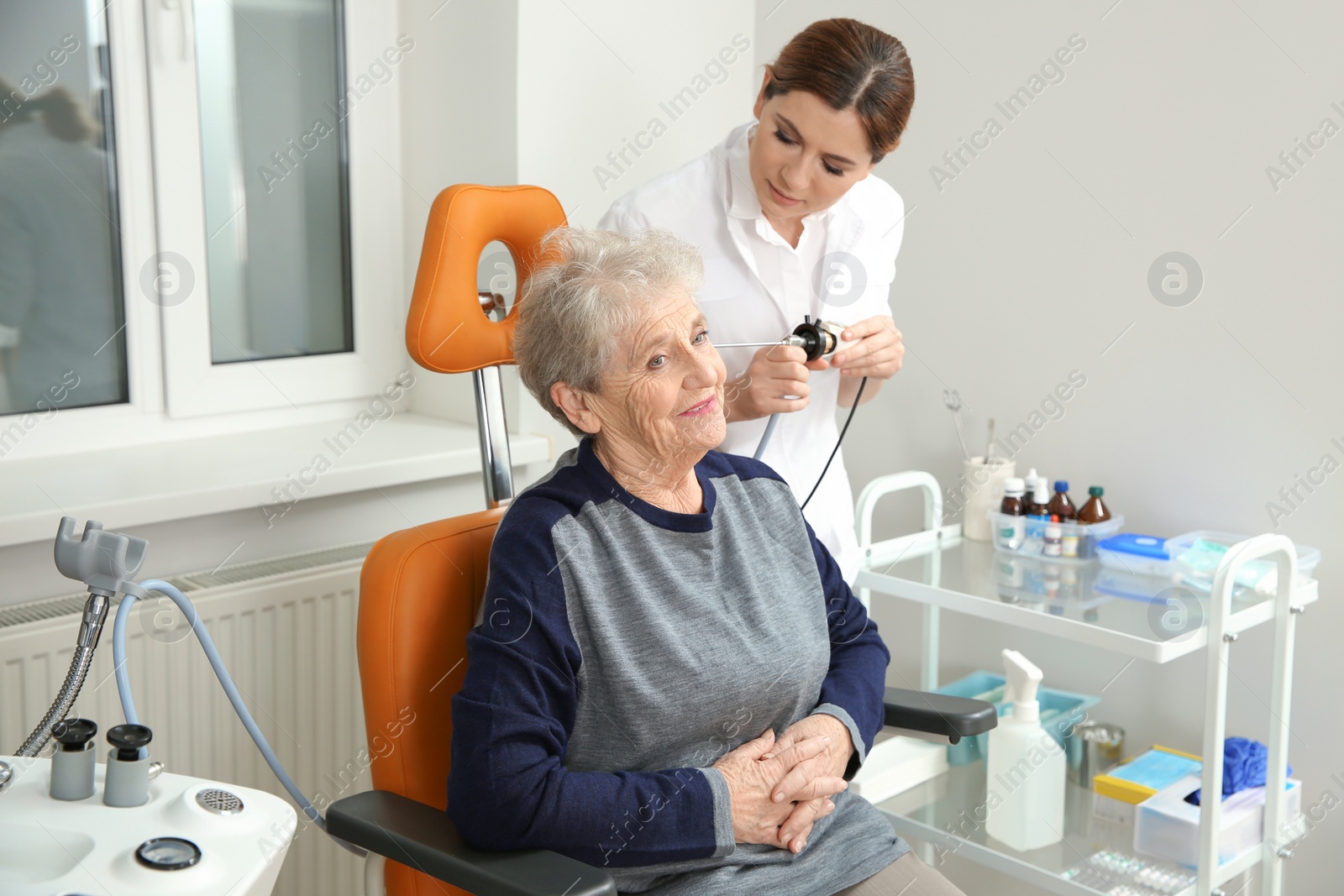 Photo of Professional otolaryngologist examining senior woman with endoscope in clinic. Hearing disorder