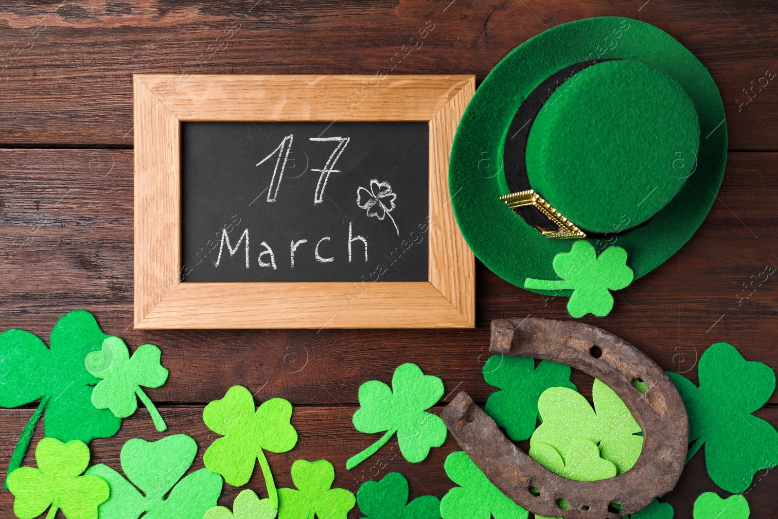 Photo of Flat lay composition with horseshoe and chalkboard on wooden background. St. Patrick's Day celebration