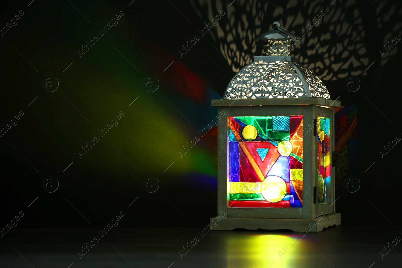 Photo of Decorative Arabic lantern on table against dark background. Space for text