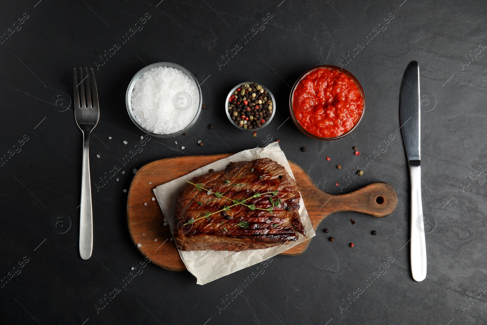 Photo of Flat lay composition with grilled meat on black table