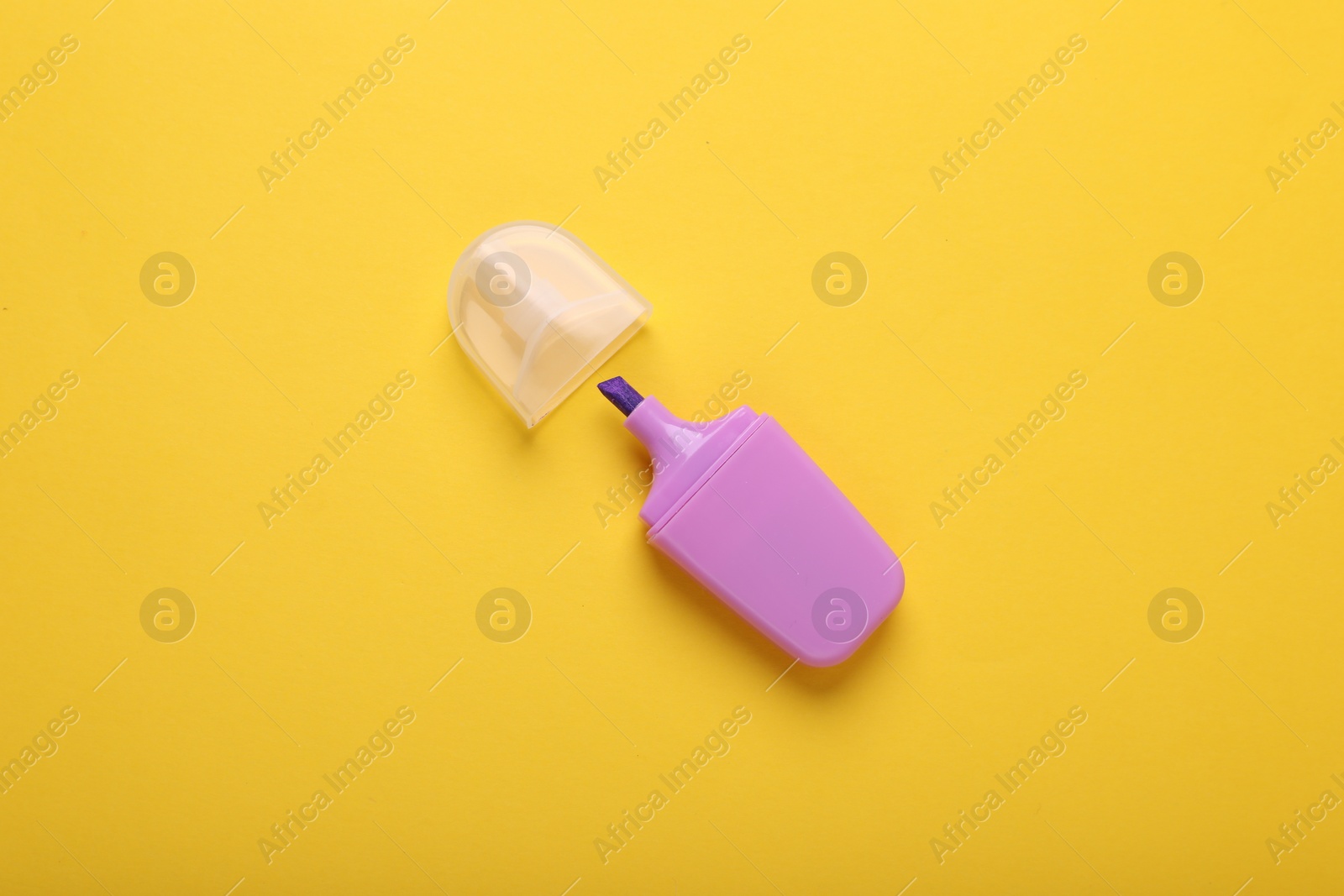 Photo of One violet marker with cap on yellow background, top view