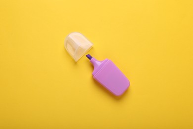 One violet marker with cap on yellow background, top view