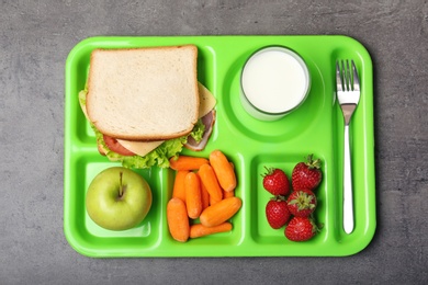 Serving tray with healthy food on gray background, top view. School lunch