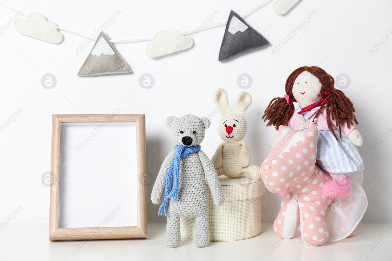 Photo of Soft toys and photo frame on table against white background, space for text. Child room interior