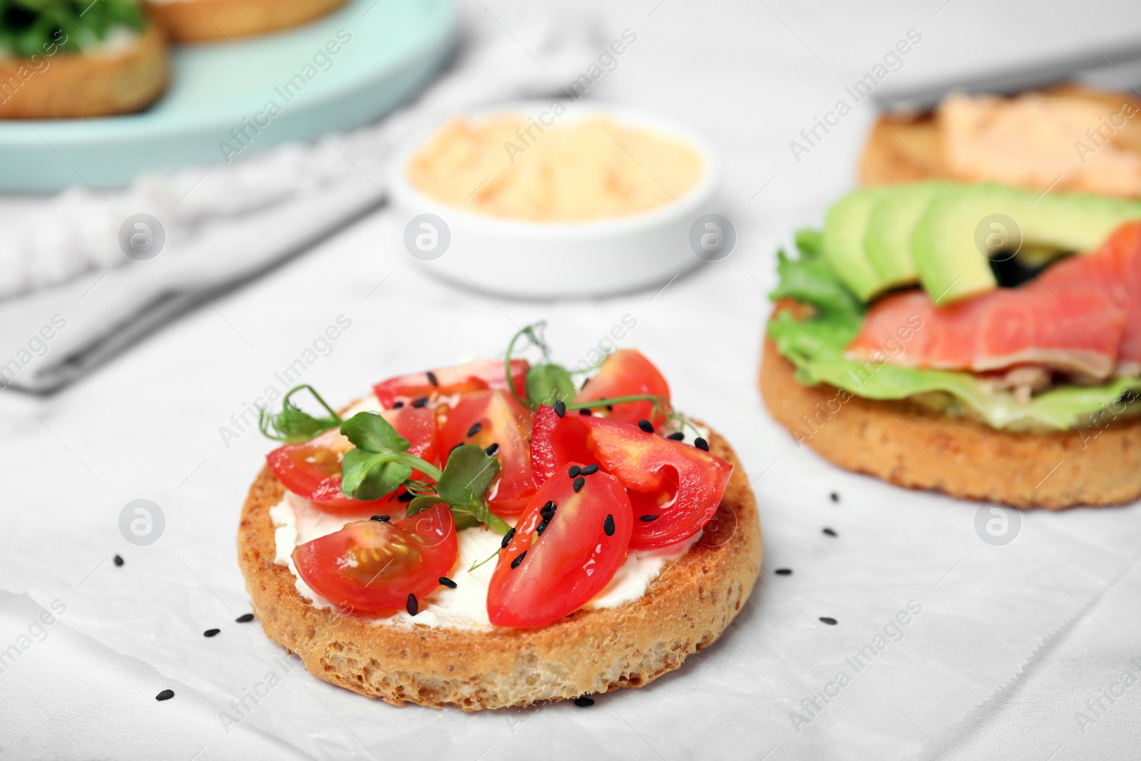 Photo of Tasty rusks with different toppings on white table, closeup