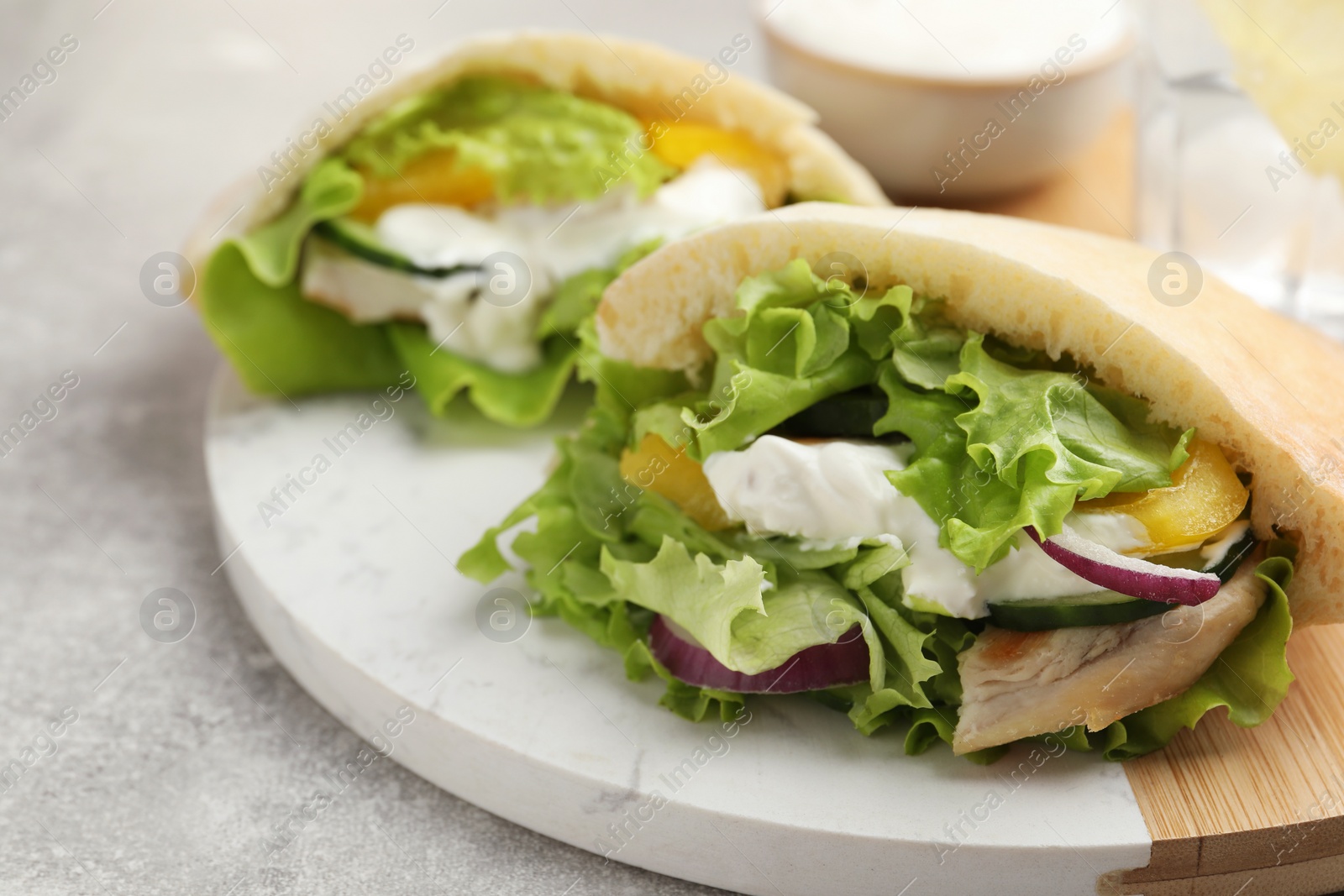 Photo of Delicious pita sandwiches with chicken breast and vegetables on light gray table, closeup