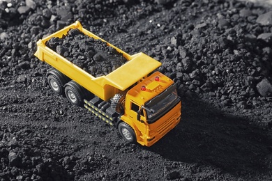 Image of Toy tipper truck with coal in field