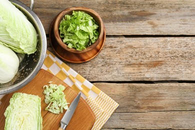 Fresh Chinese cabbages and knife on wooden table, top view. Space for text