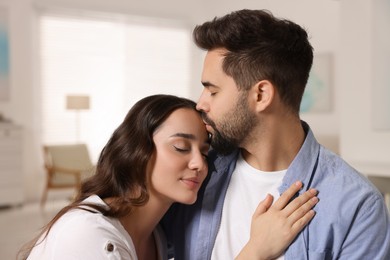 Photo of Cute couple. Man kissing his girlfriend at home