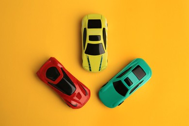 Photo of Different bright cars on yellow background, flat lay. Children`s toys