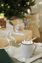 Photo of Cup of cocoa with wafer tubes on table indoors. Christmas celebration