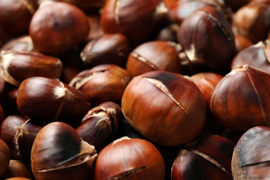 Pile of delicious edible roasted chestnuts as background, closeup