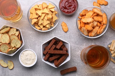 Different crispy rusks, beer and dip sauces on light table, flat lay