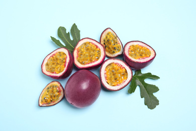 Fresh ripe passion fruits (maracuyas) with green leaves on light blue background, flat lay