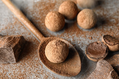 Composition with spoon and chocolate truffles on grey background