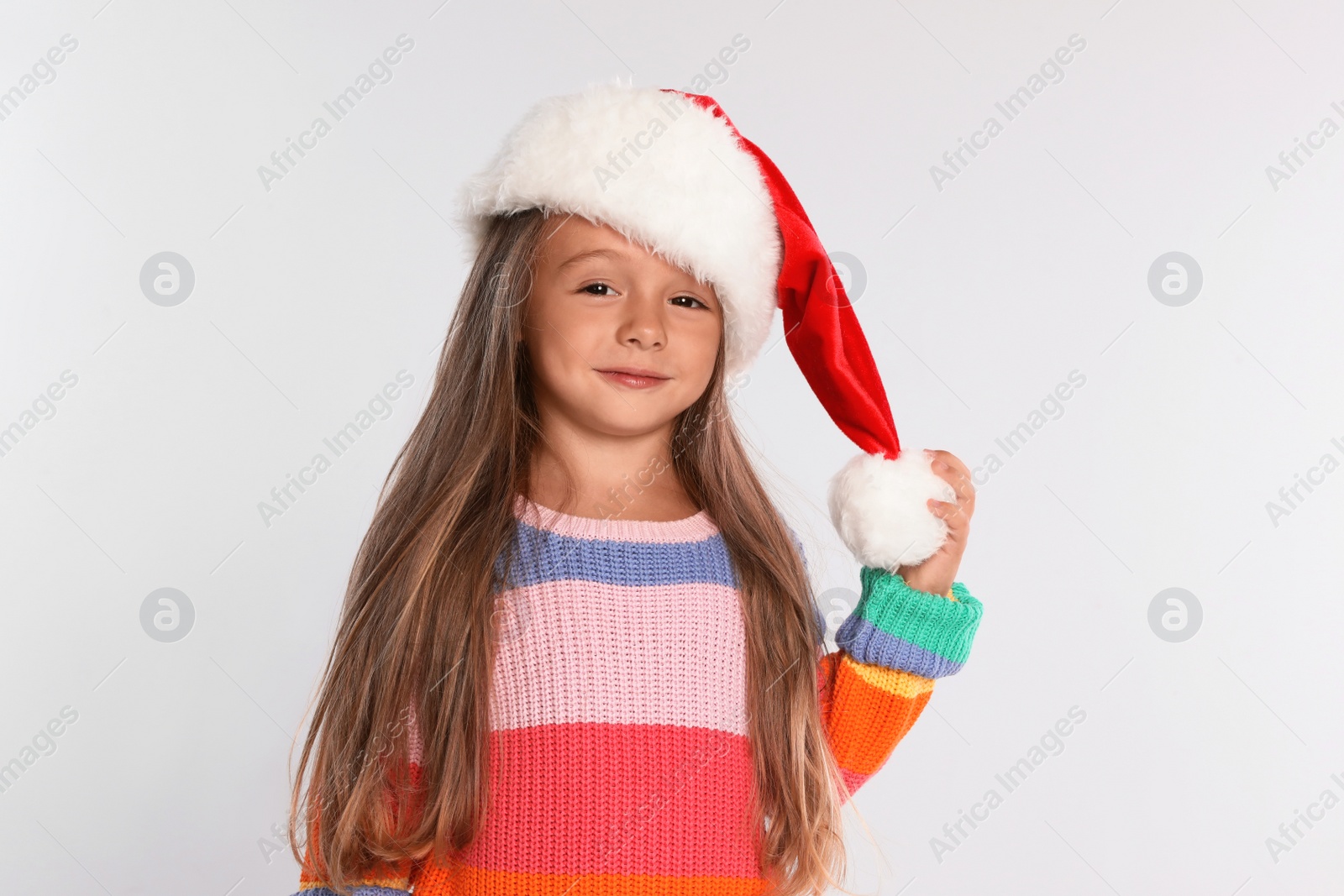 Photo of Happy little child in Santa hat on light grey background. Christmas celebration