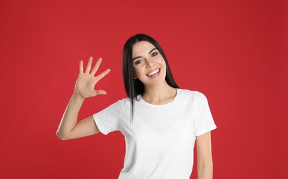 Photo of Woman showing number five with her hand on red background