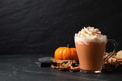 Photo of Delicious pumpkin latte on black slate table. Space for text