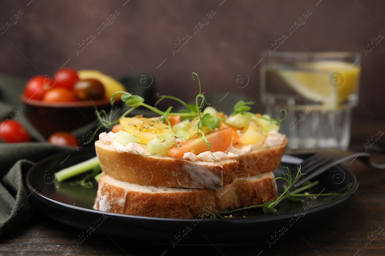 Photo of Tasty vegan sandwich with tomatoes, celery and microgreens on wooden table, closeup