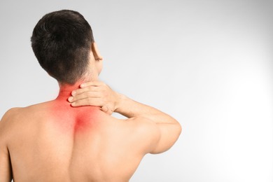 Image of Young man suffering from neck pain on light background