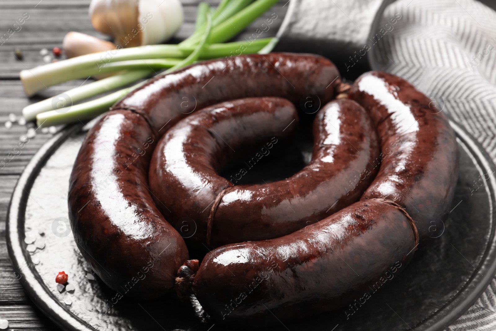 Photo of Tasty blood sausages served on black wooden table, closeup