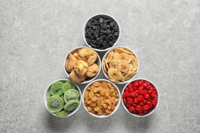 Photo of Bowls with different dried fruits on grey background, flat lay. Healthy food