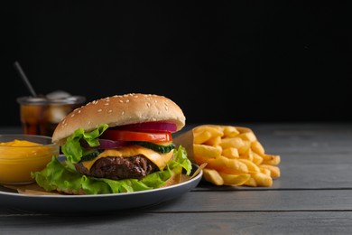 Delicious burger, soda drink and french fries served on grey wooden table. Space for text