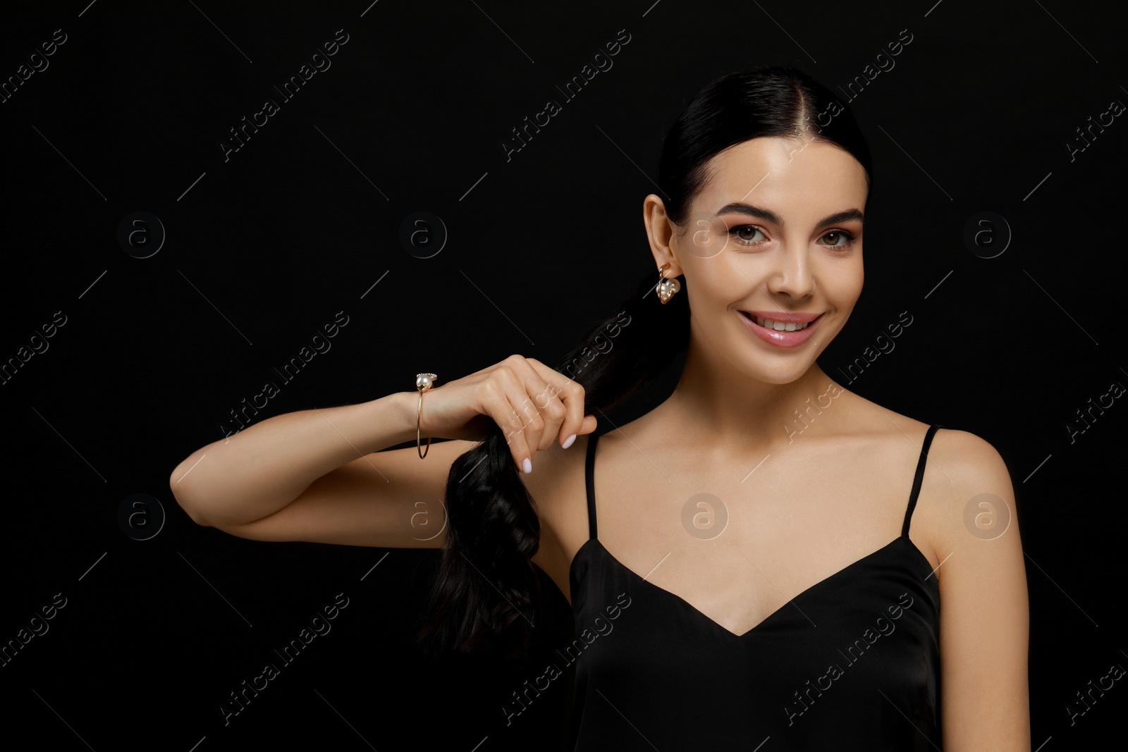 Photo of Young woman with elegant pearl jewelry on black background