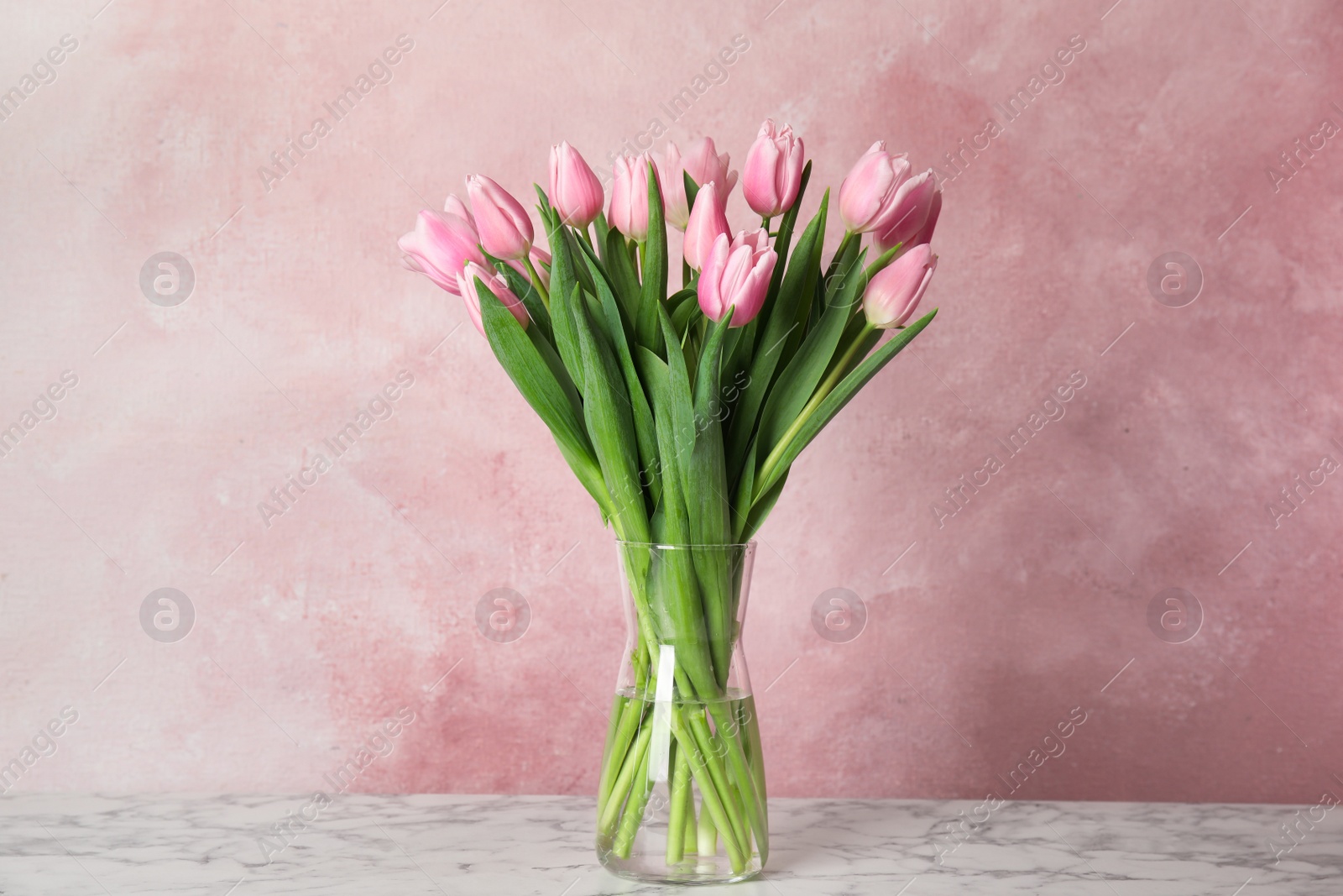 Photo of Beautiful pink spring tulips on marble table