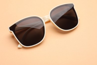 Photo of New stylish elegant sunglasses on beige background, closeup