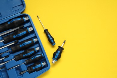 Photo of Set of screwdrivers and toolbox on yellow table, flat lay. Space for text