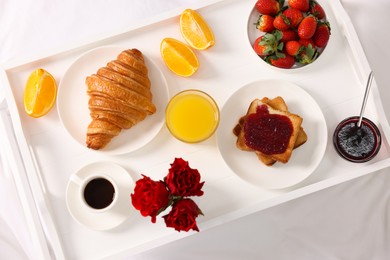 Photo of Tray with delicious breakfast on bed, top view