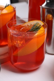 Photo of Aperol spritz cocktail, rosemary and orange slices on white wooden table, closeup