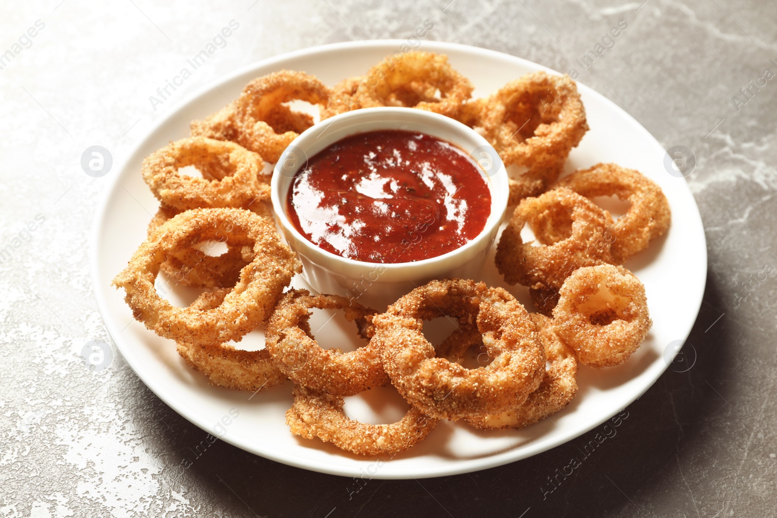 Photo of Homemade crunchy fried onion rings with sauce on color table