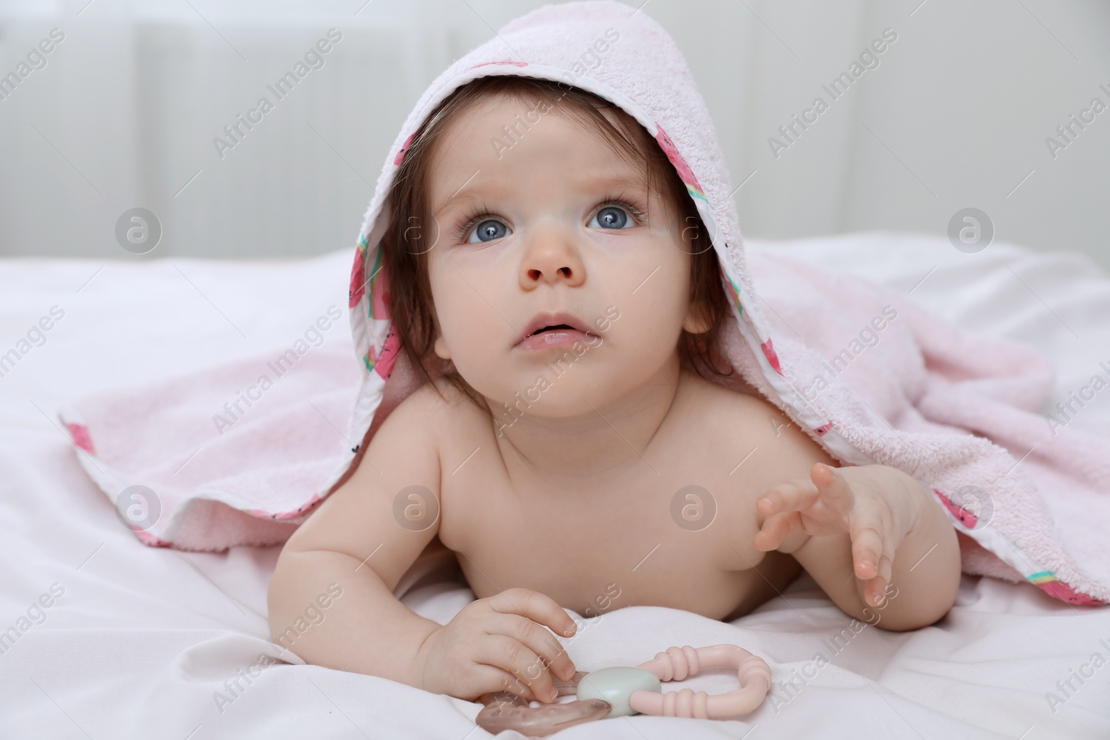 Photo of Cute little baby in hooded towel after bathing on bed at home