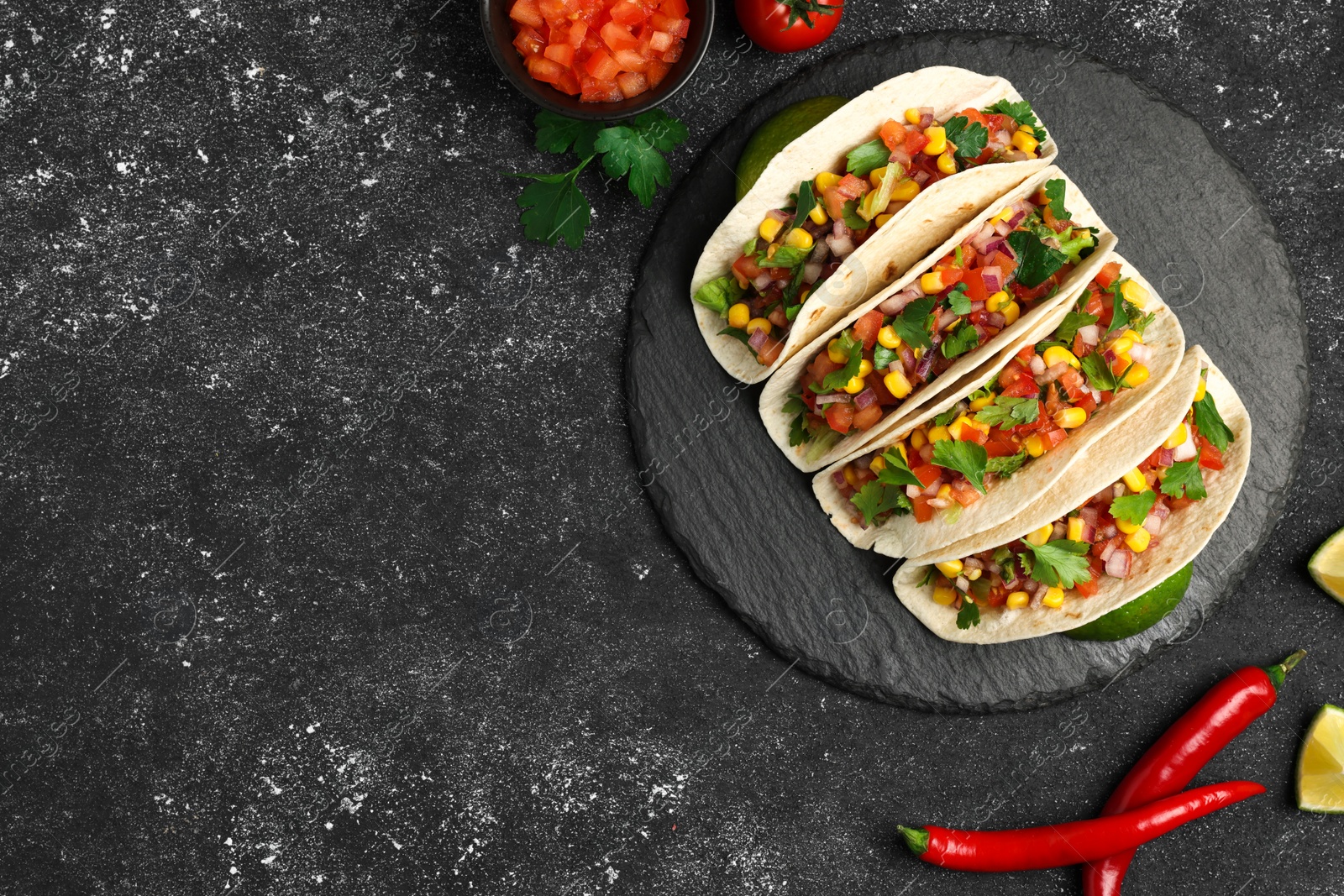 Photo of Tasty tacos with vegetables on black textured table, flat lay. Space for text