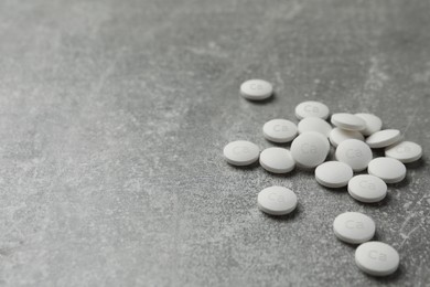 Photo of Pile of calcium supplement pills on grey table, space for text