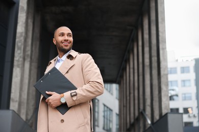 Photo of Happy man with clipboard outdoors, space for text. Lawyer, businessman, accountant or manager