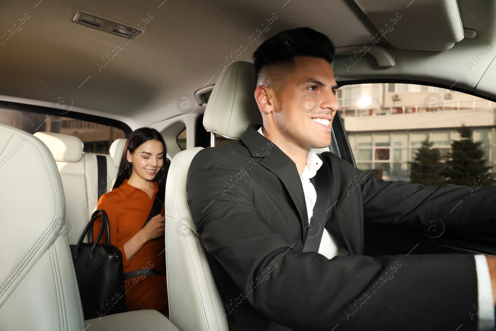 Photo of Young woman and taxi driver in modern car