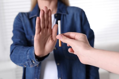 Woman refusing cigarette on light background, closeup. Quitting smoking concept